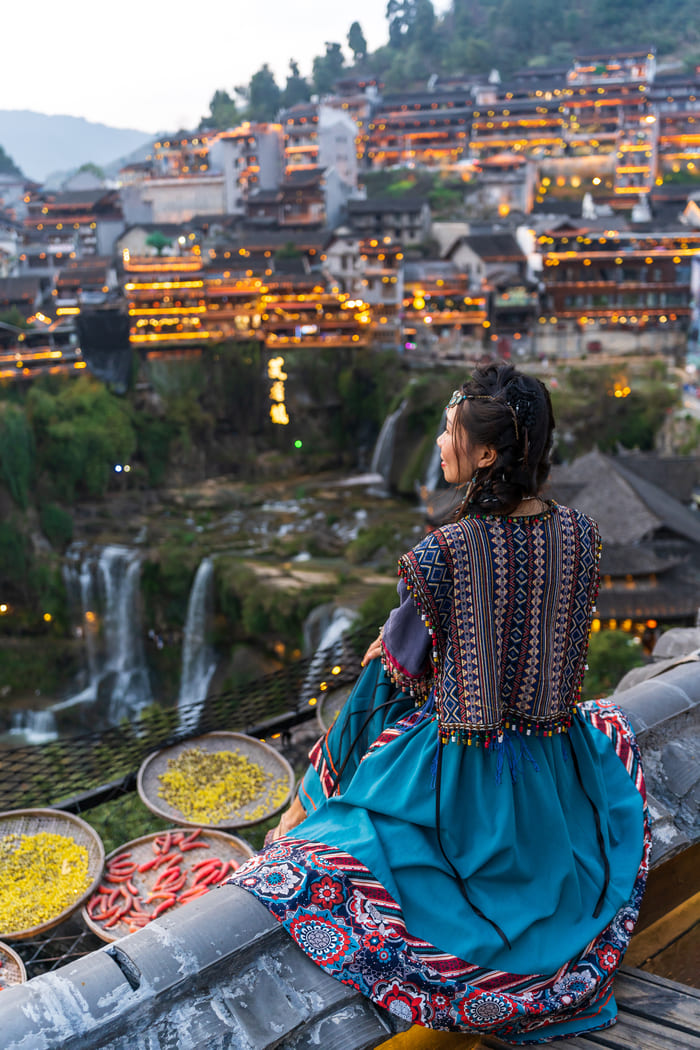 Mujer sentada frente a la ciudad de lijiang